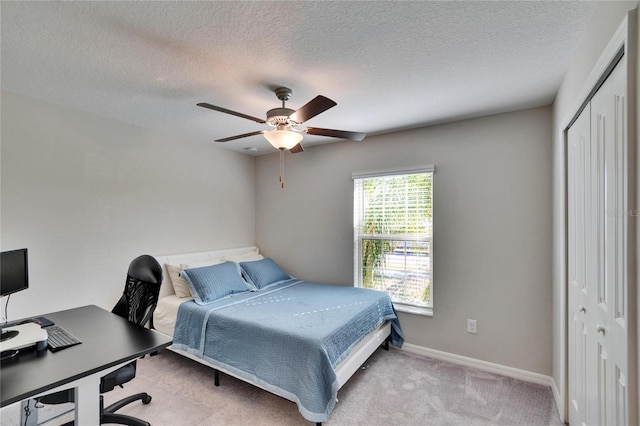 bedroom featuring a textured ceiling, a closet, light carpet, and ceiling fan