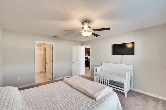 carpeted bedroom featuring ceiling fan and ensuite bath