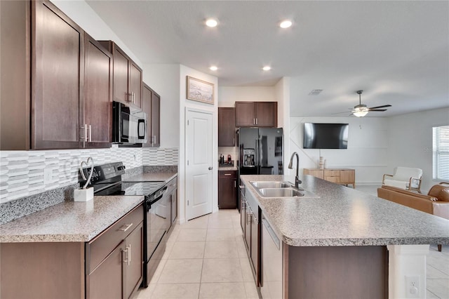 kitchen with a center island with sink, black appliances, sink, dark brown cabinets, and decorative backsplash