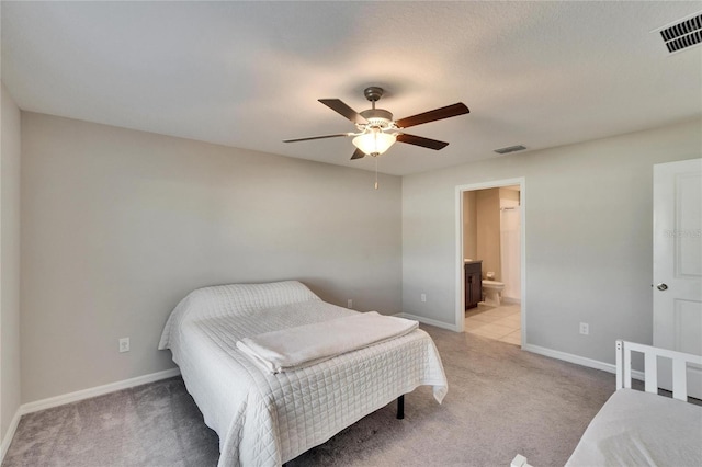 bedroom with light carpet, ensuite bath, and ceiling fan