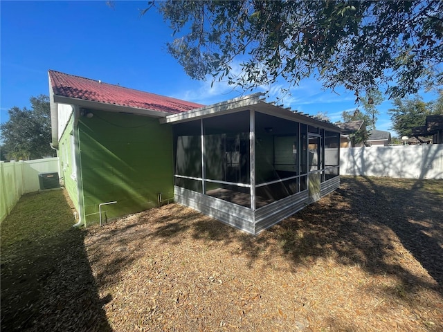 rear view of property with a yard, a sunroom, and central air condition unit