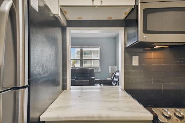 kitchen with tasteful backsplash, white cabinetry, and appliances with stainless steel finishes