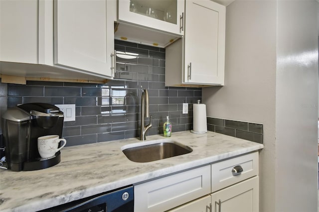 kitchen featuring sink, white cabinetry, black dishwasher, light stone counters, and tasteful backsplash