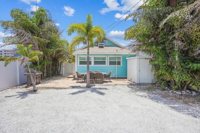 back of property with a storage shed and a patio