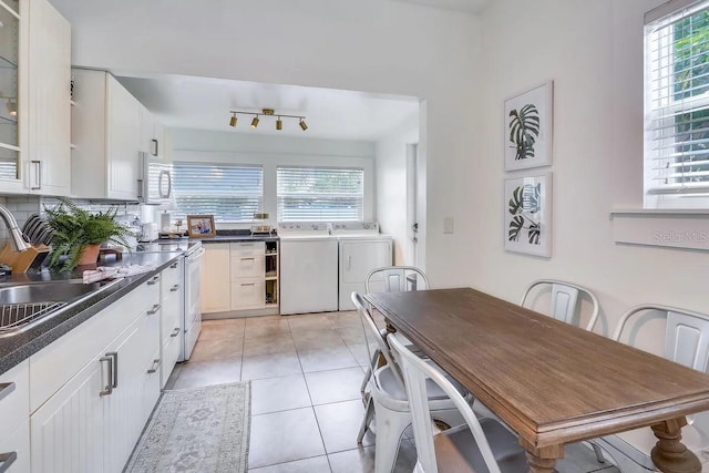 kitchen featuring sink, light tile patterned floors, white electric range oven, washer and dryer, and white cabinets