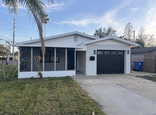 single story home featuring a garage, a sunroom, and a front yard