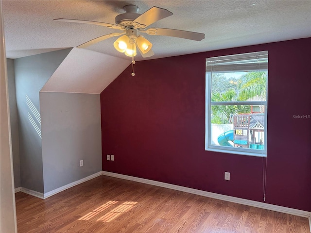 additional living space with wood-type flooring, lofted ceiling, ceiling fan, and a textured ceiling