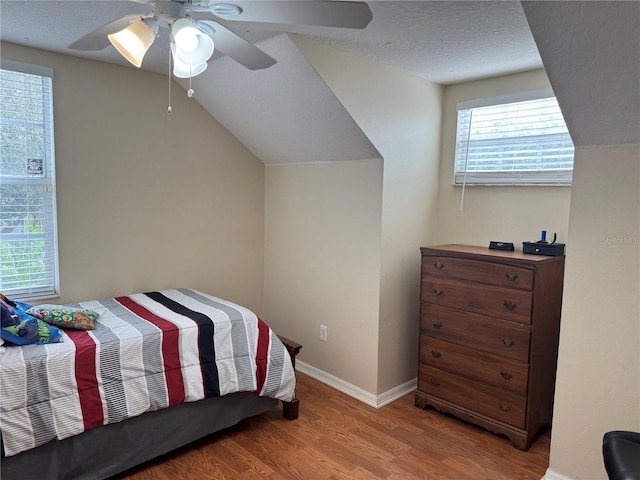 bedroom with ceiling fan, lofted ceiling, light hardwood / wood-style flooring, and a textured ceiling