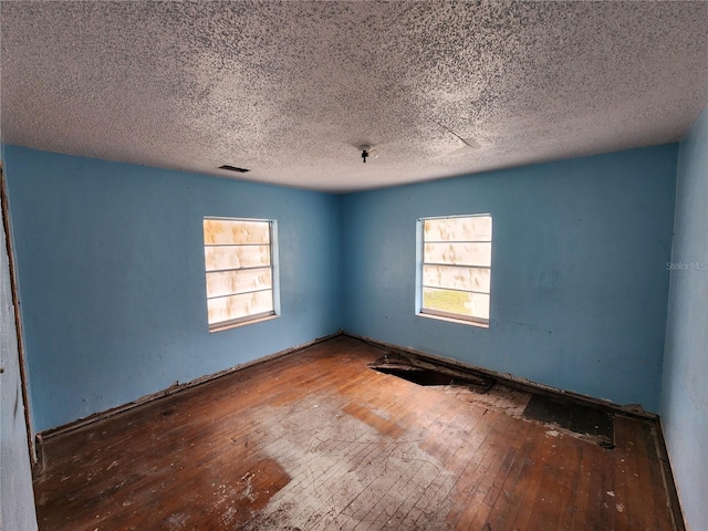 spare room with hardwood / wood-style floors and a textured ceiling