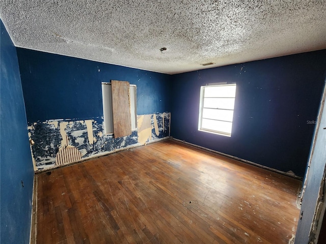 unfurnished room with hardwood / wood-style flooring and a textured ceiling