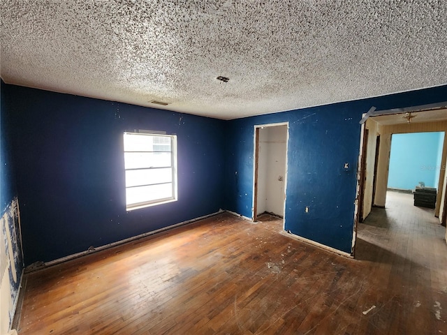 unfurnished bedroom featuring hardwood / wood-style flooring, a textured ceiling, and a closet