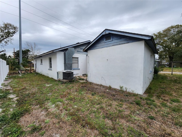 view of side of home with cooling unit and a lawn