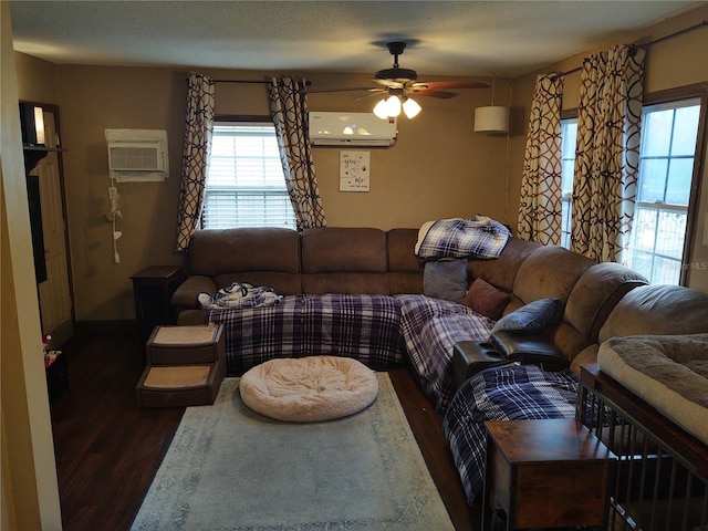 living room featuring an AC wall unit, dark wood-type flooring, and a wealth of natural light