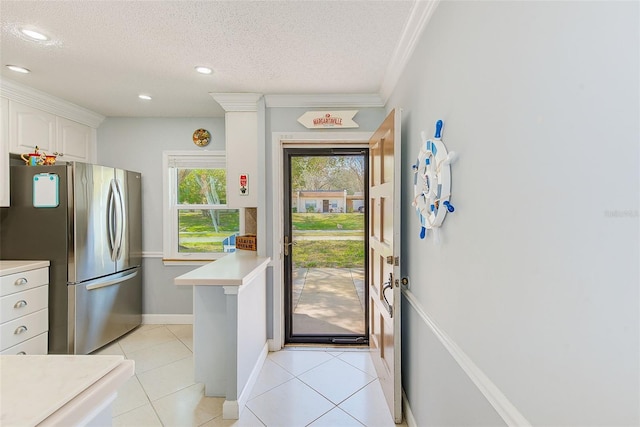 kitchen featuring a textured ceiling, light tile patterned floors, white cabinets, and stainless steel refrigerator