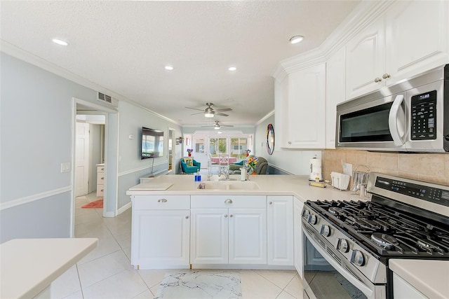 kitchen with sink, ornamental molding, kitchen peninsula, stainless steel appliances, and white cabinets