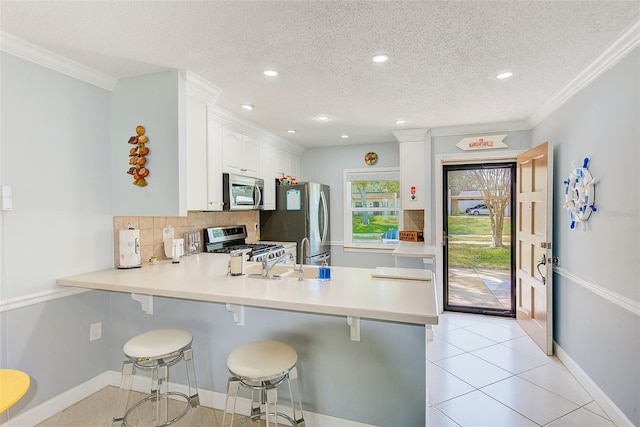 kitchen with white cabinetry, a kitchen breakfast bar, stainless steel appliances, and kitchen peninsula