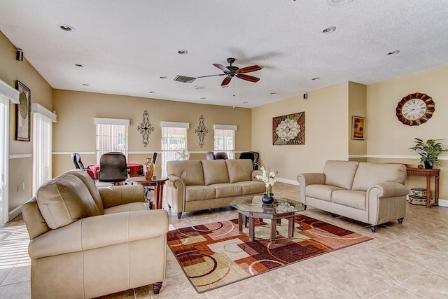 tiled living room with ceiling fan and a textured ceiling