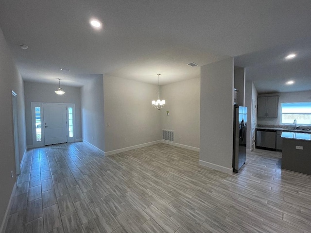 unfurnished living room featuring an inviting chandelier, sink, and wood-type flooring