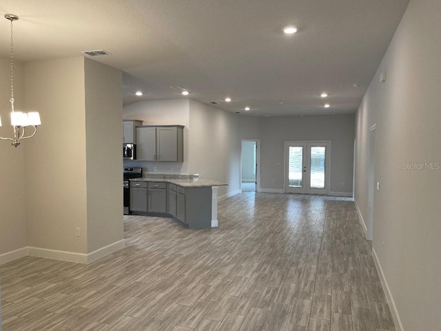 unfurnished living room with a chandelier, light wood-type flooring, and french doors