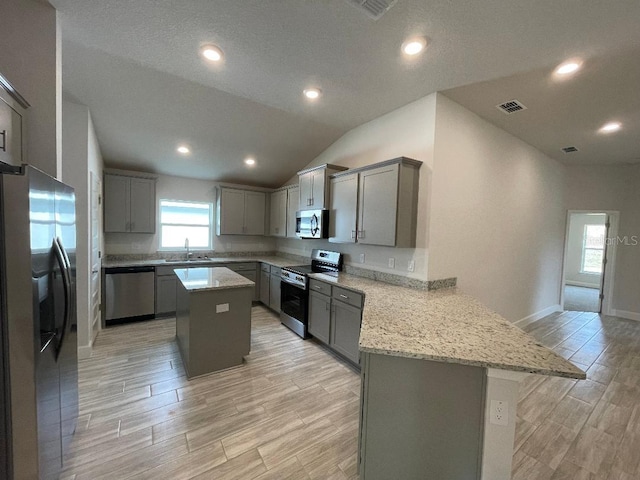 kitchen featuring gray cabinets, appliances with stainless steel finishes, sink, a center island, and kitchen peninsula