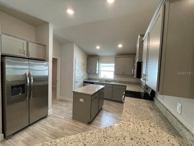 kitchen with gray cabinets, a kitchen island, sink, light stone counters, and stainless steel appliances