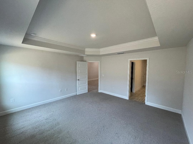 carpeted spare room featuring a raised ceiling and crown molding