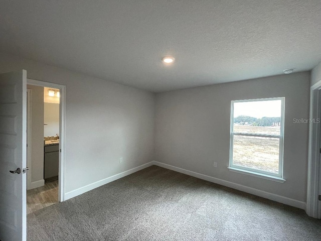 carpeted empty room featuring a textured ceiling