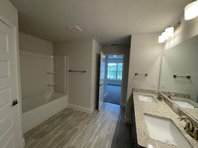 bathroom with vanity, hardwood / wood-style floors, tub / shower combination, and a textured ceiling