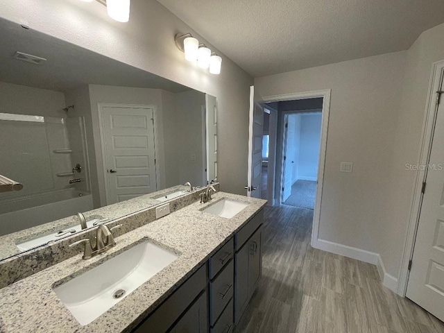 bathroom with shower / bathing tub combination, hardwood / wood-style floors, vanity, and a textured ceiling