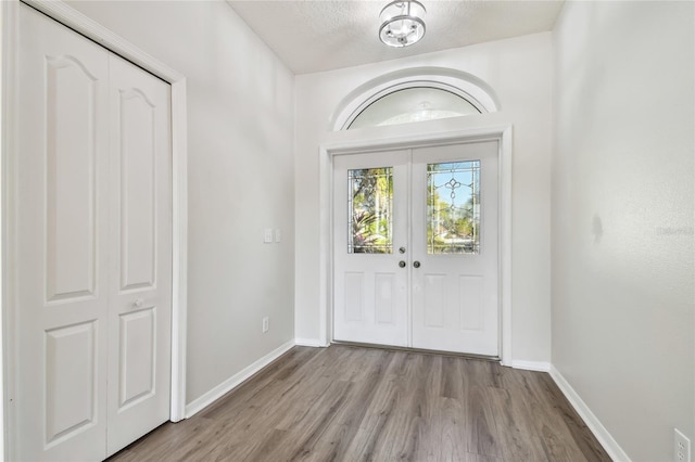 foyer entrance featuring french doors, a textured ceiling, and light wood-type flooring