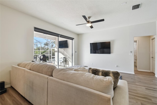 living room featuring wood-type flooring, a textured ceiling, and ceiling fan