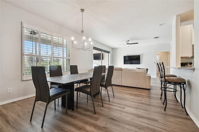 dining room with hardwood / wood-style flooring, ceiling fan with notable chandelier, and a textured ceiling