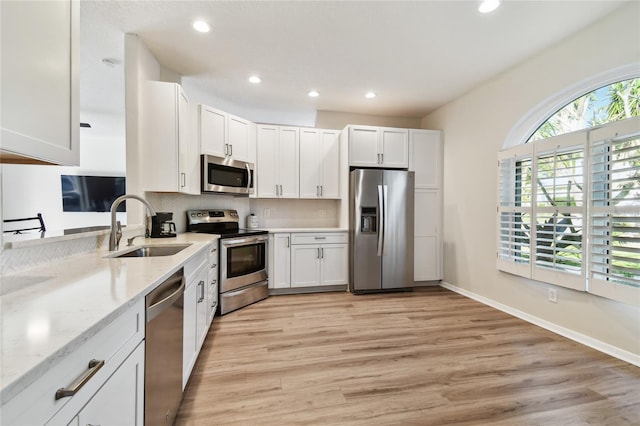 kitchen with light stone counters, stainless steel appliances, sink, and white cabinets