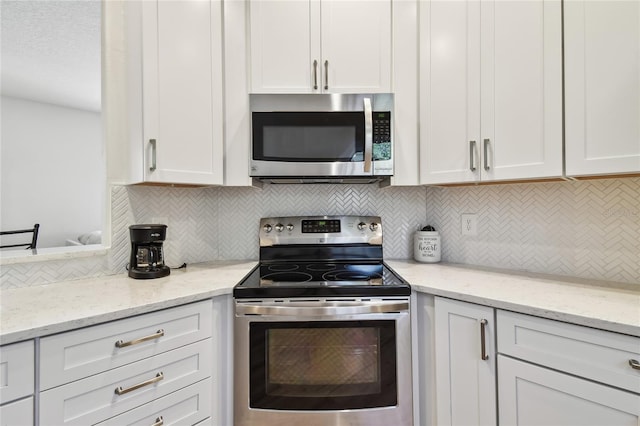 kitchen featuring light stone counters, decorative backsplash, white cabinets, and appliances with stainless steel finishes