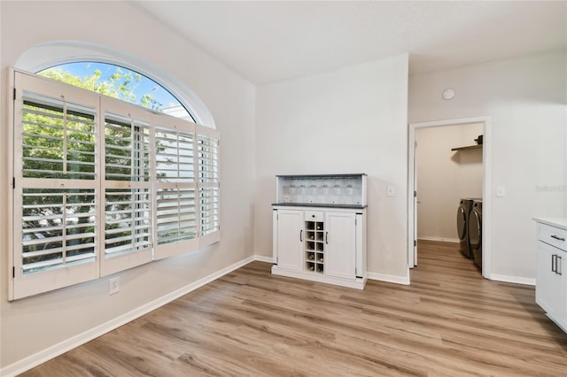 bar featuring white cabinetry, separate washer and dryer, and light hardwood / wood-style floors