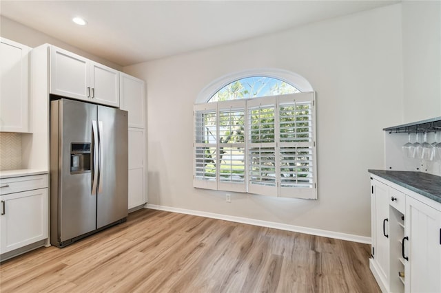 kitchen with stainless steel refrigerator with ice dispenser, tasteful backsplash, light hardwood / wood-style flooring, and white cabinets