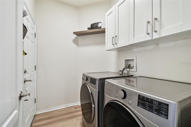 laundry room featuring cabinets, washer and dryer, and light hardwood / wood-style flooring