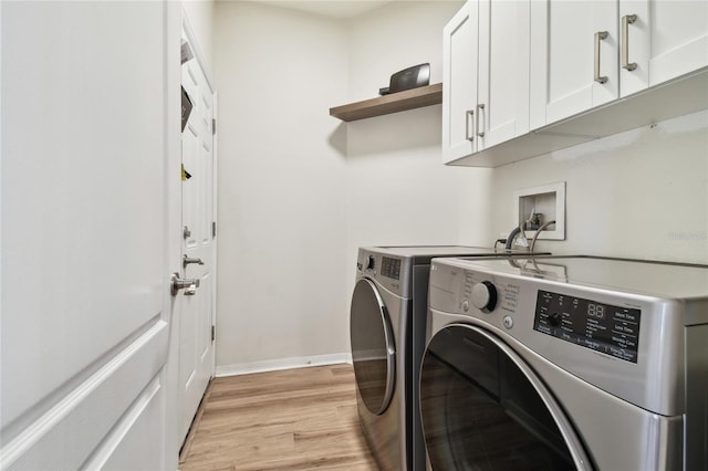 laundry area featuring cabinets, washing machine and clothes dryer, and light wood-type flooring