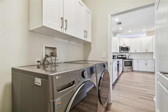 washroom with cabinets, separate washer and dryer, and light hardwood / wood-style flooring