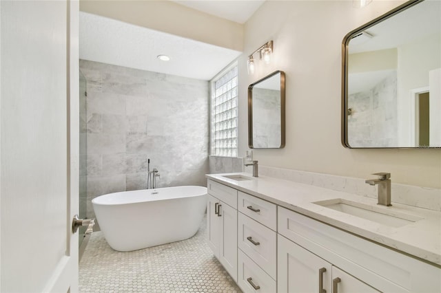 bathroom with tile patterned floors, a bathing tub, vanity, and tile walls