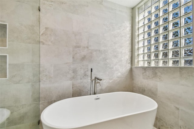 bathroom featuring tile walls and a tub to relax in