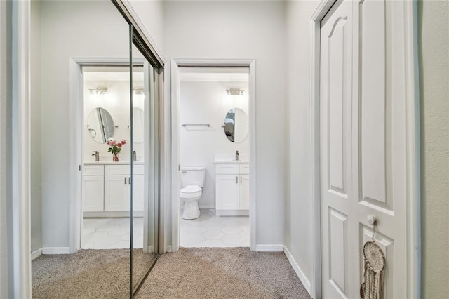 hall featuring sink and light colored carpet