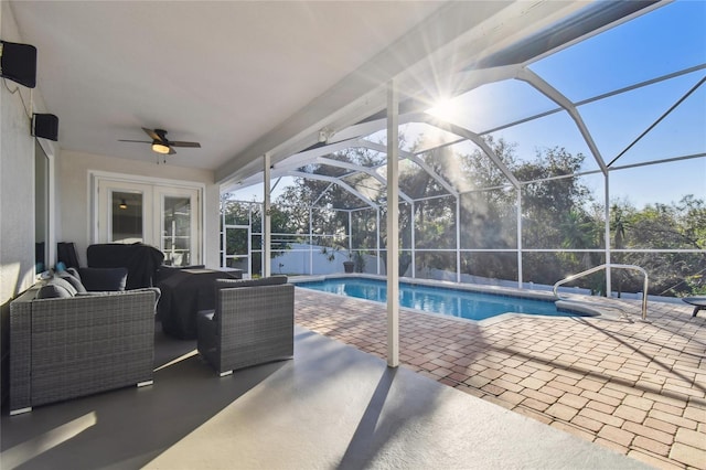 view of pool featuring outdoor lounge area, a patio, ceiling fan, and glass enclosure