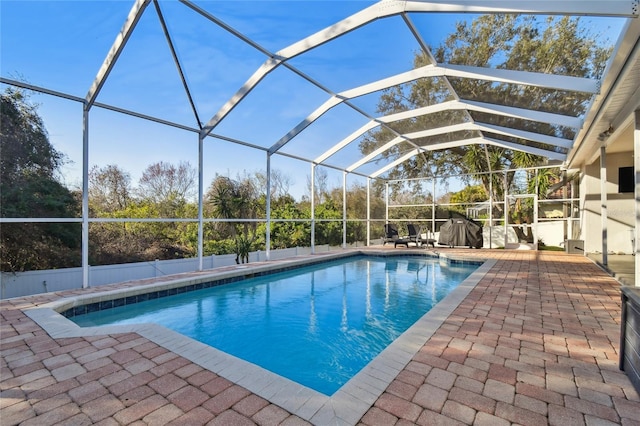 view of swimming pool featuring a patio area and glass enclosure