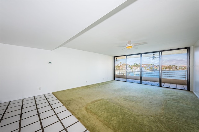 unfurnished room with a ceiling fan, floor to ceiling windows, and carpet flooring