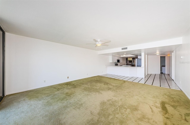 unfurnished living room featuring carpet floors, ceiling fan, visible vents, and tile patterned floors