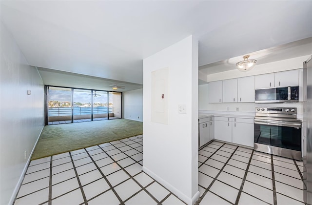 kitchen featuring light colored carpet, open floor plan, stainless steel appliances, light countertops, and white cabinetry