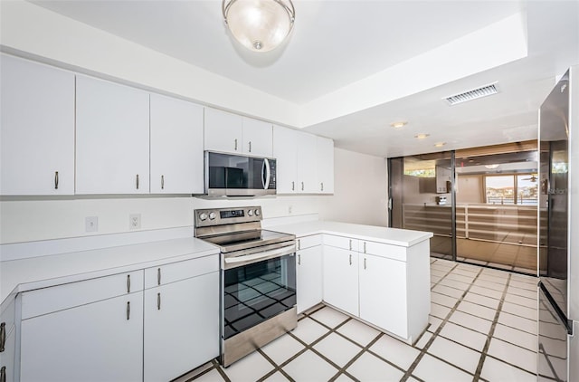 kitchen with stainless steel appliances, a peninsula, visible vents, white cabinetry, and light countertops