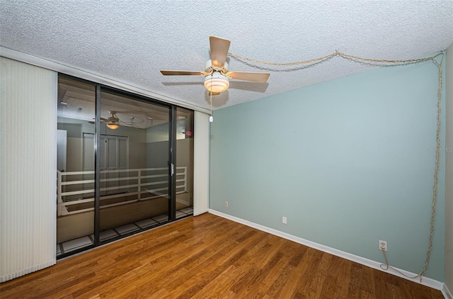 spare room featuring a textured ceiling, wood finished floors, a ceiling fan, and baseboards