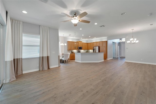 unfurnished living room with ceiling fan with notable chandelier and light hardwood / wood-style floors